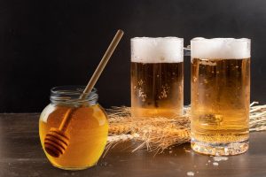 Glasses of homebrewed beer and jar of honey